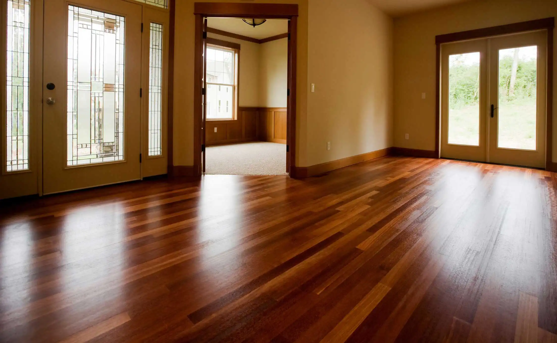 Rich hardwood running through an entry hall and out toward french doors, meeting the trim and thresholds cleanly